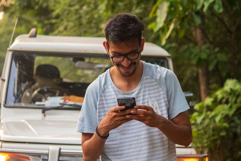 man in white crew neck t-shirt holding black smartphone